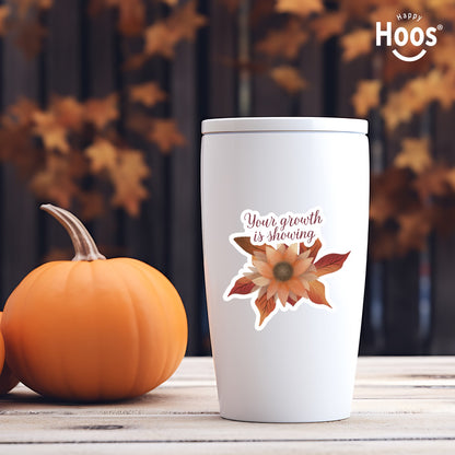 white tumbler with Autumn Growth sticker featuring a watercolor sunflower in autumn tones of orange, rust, and brown with fall leaves, and burgundy script lettering reading "Your growth is showing" at the top, measuring 3.3 by 2.9 inches