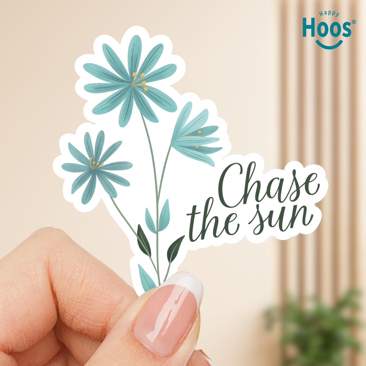 Sticker with blue flowers and 'Chase the sun' text held by a hand, with 'Happy Hoos' brand visible.