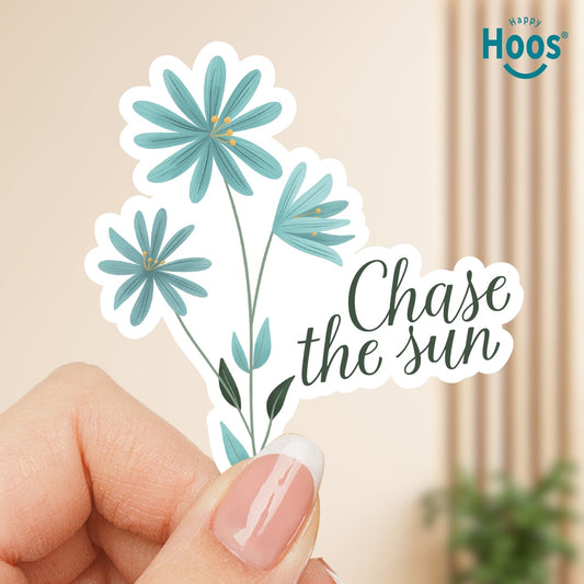 Sticker with blue flowers and 'Chase the sun' text held by a hand, with 'Happy Hoos' brand visible.