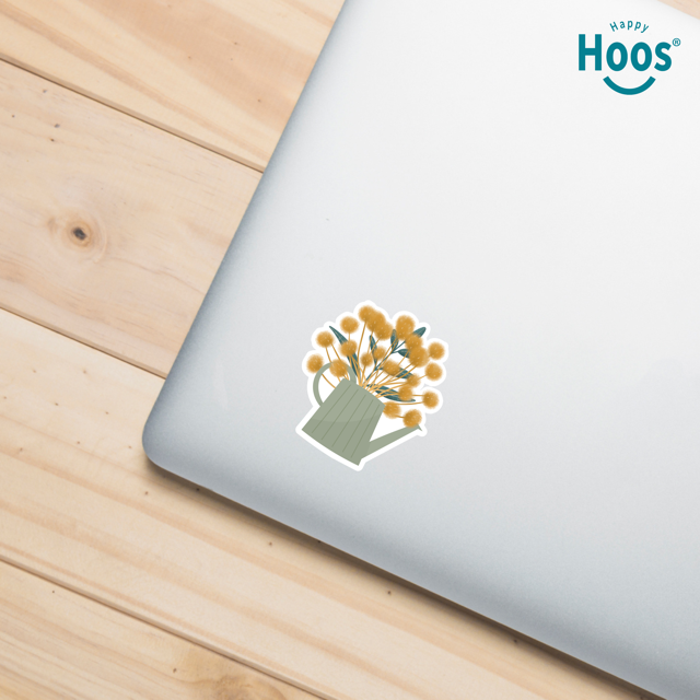 Laptop with a floral sticker on a wooden surface, featuring the 'Happy Hoos' brand.