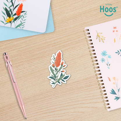 Floral sticker on a wooden surface with a pen and notebook, featuring the brand 'Happy Hoos'.