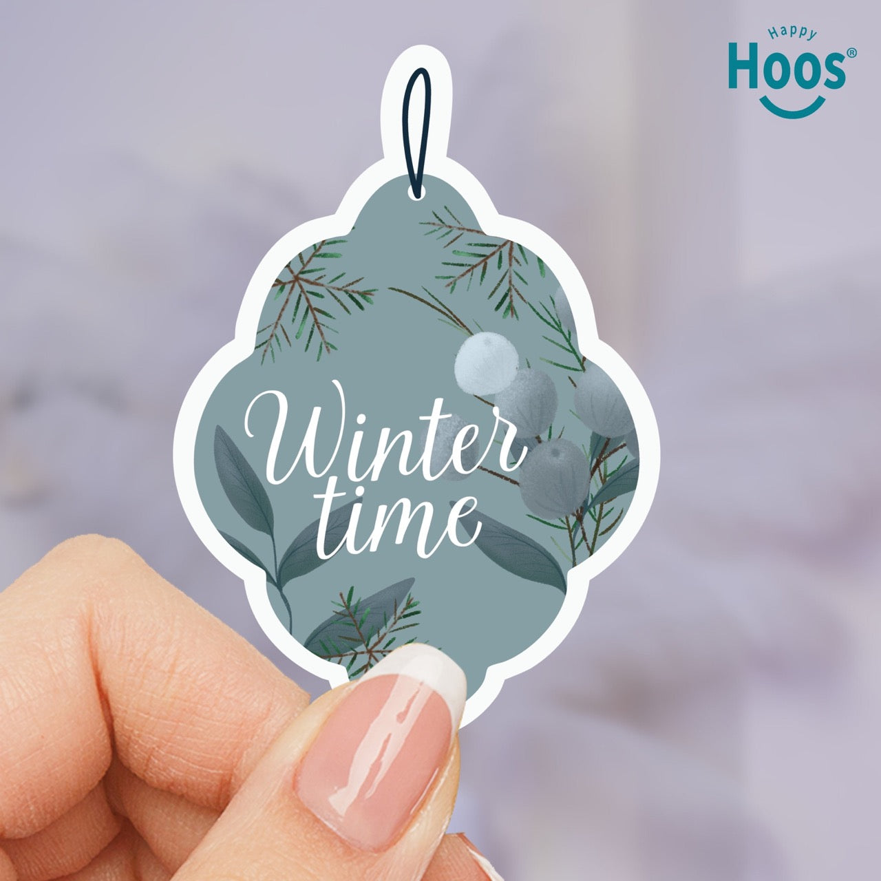 Decorative ornament sticker with 'Winter time' text held by a hand, featuring the brand 'Happy Hoos'.