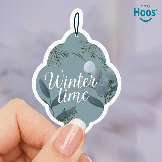 Decorative ornament sticker with 'Winter time' text held by a hand, featuring the brand 'Happy Hoos'.
