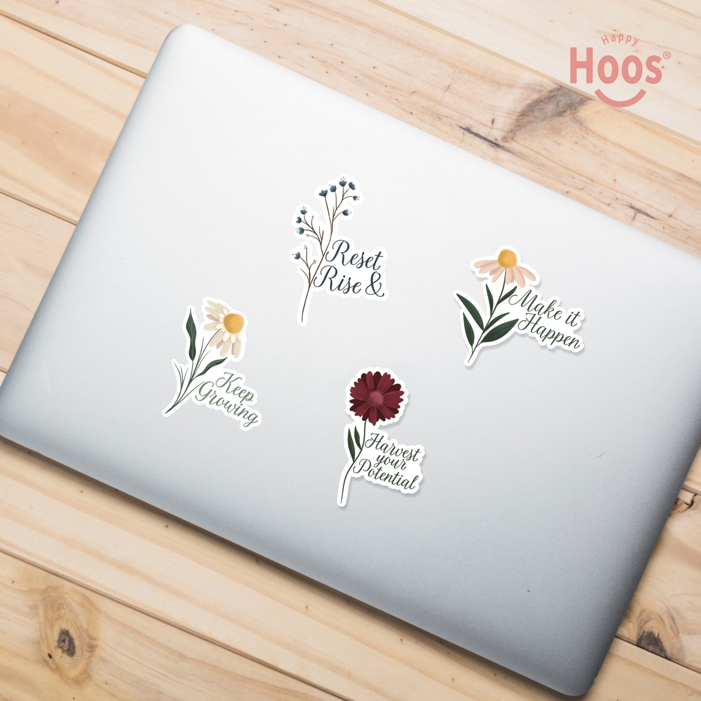 Laptop decorated with Goal Getter stickers: blue berry branches with "Reset & Rise", white daisy with "Keep Growing", daisy with "Make it Happen", burgundy flower with "Harvest your Potential"