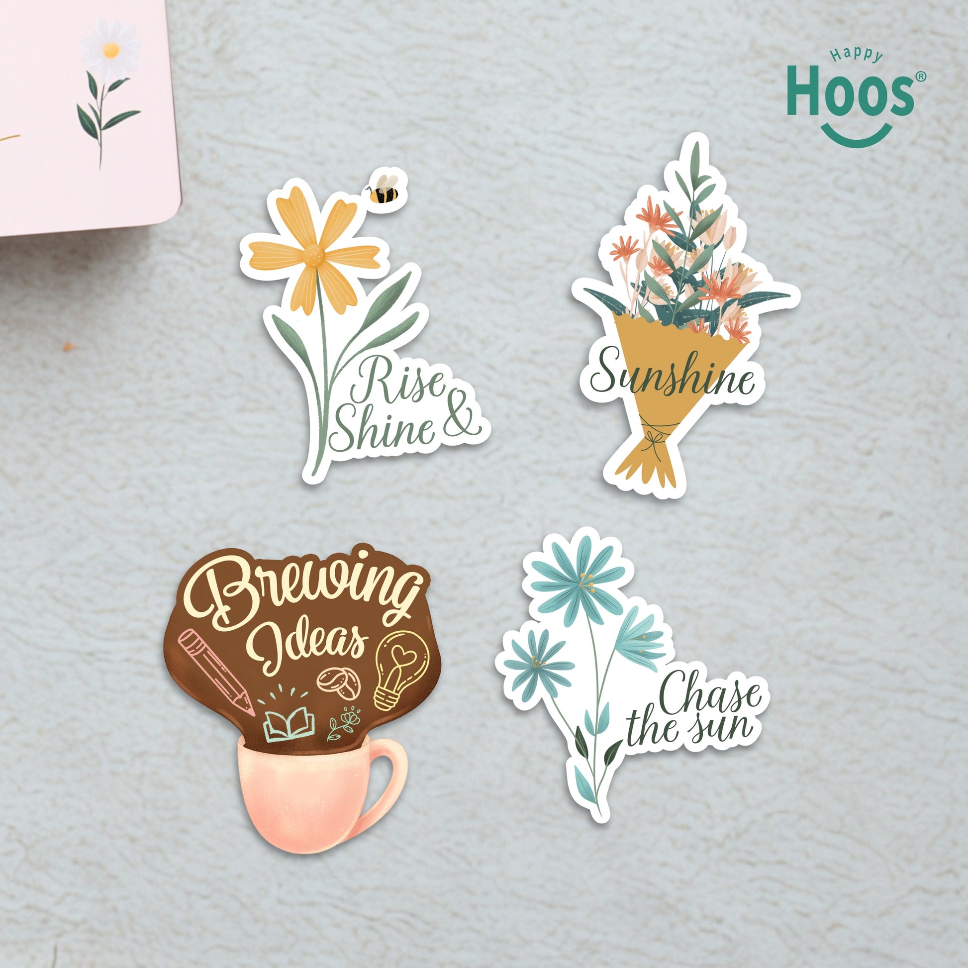 Four Morning Motivation stickers on surface: yellow daisy with bee and "Rise & Shine", flower bouquet with "Sunshine", coffee mug with "Brewing Ideas", blue flowers with "Chase the sun"