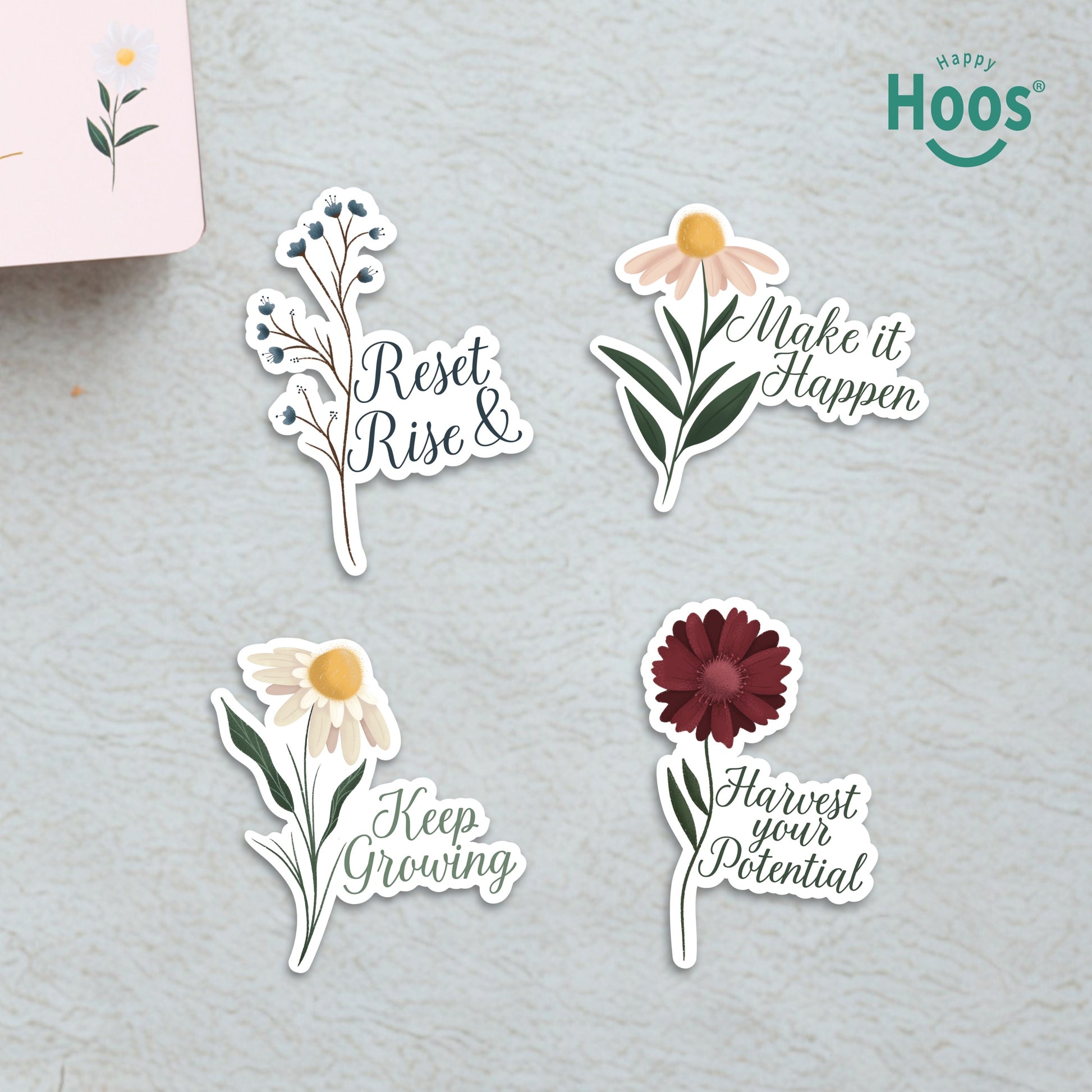Four Goal Getter stickers on surface: blue berry branches with "Reset & Rise", daisy with "Make it Happen", white daisy with "Keep Growing", burgundy flower with "Harvest your Potential"