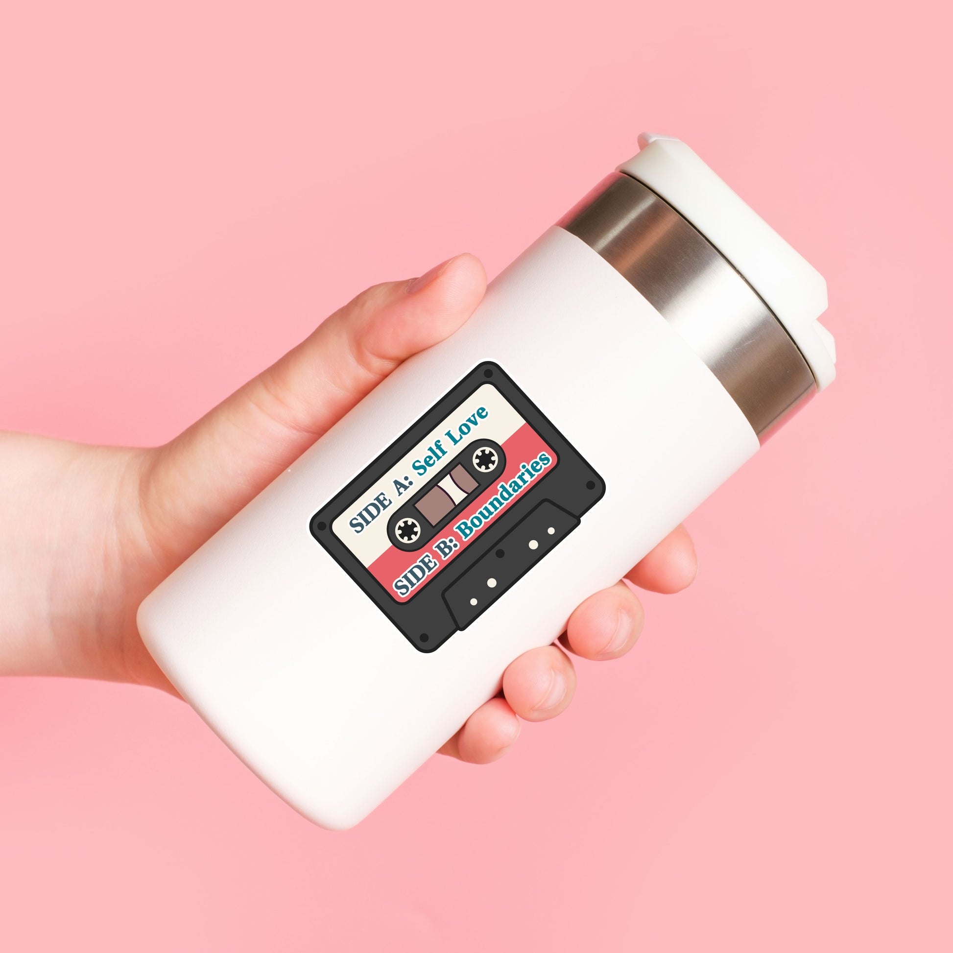 White mug with cassette tape design held against a pink background