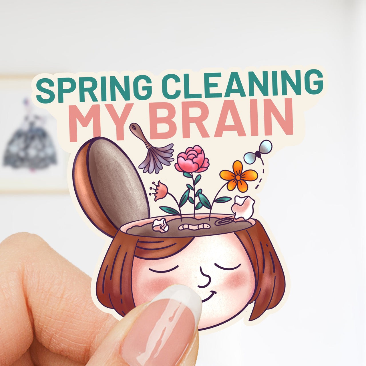 Woman holding Spring Cleaning My Brain waterproof sticker featuring a smiling face with flowers growing from an open head, made for self care, overthinkers, mental reset, planners, laptops, and water bottles.