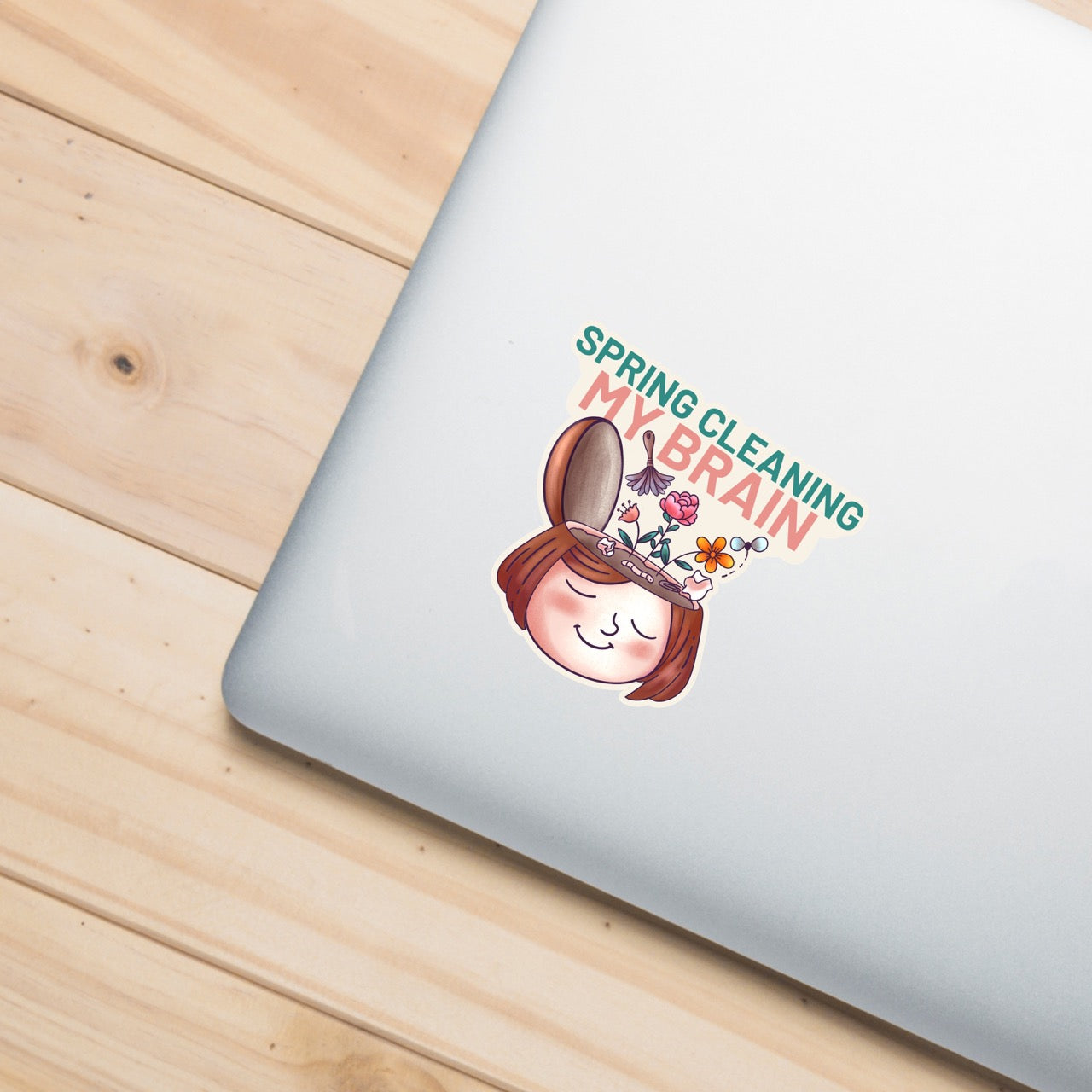 Spring Cleaning My Brain waterproof sticker on a laptop featuring a smiling face with flowers growing from an open head, made for self care, overthinkers, mental reset, planners, laptops, and water bottles.